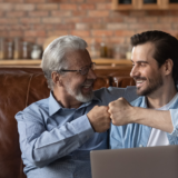 Excited small business partners (older & younger man, fist-bumping image)