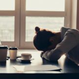 Fatigued woman slumped over desk (image)